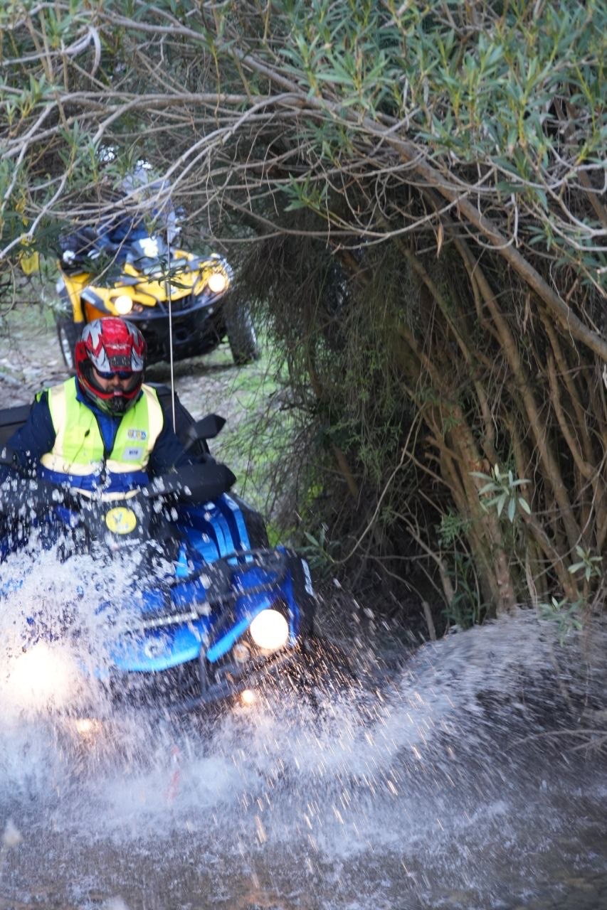 Quad che guada il torrente tra gli spruzzi d'acqua